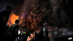 Firefighters and rescuers gather outside a computer shop hit in an Israeli airstrike in central Beirut, Nov. 17, 2024.
