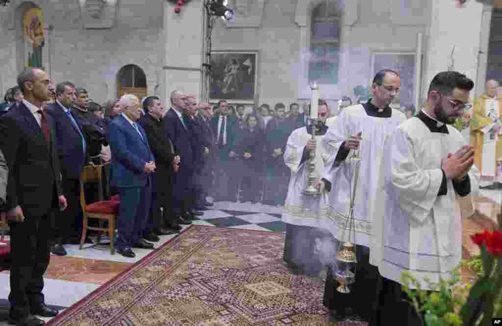 Palestinian President Mahmoud Abbas, second from left in front, attends a Christmas midnight mass at Saint Catherine's Church, in the Church of the Nativity, traditionally recognized by Christians to be the birthplace of Jesus Christ, in the West Bank city of Bethlehem, Dec. 25, 2018.