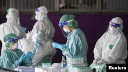 បុគ្គលិក​សុខាភិបាល​ថៃ​ត្រៀម​ប្រមូល​សំណាក​ពី​ពលករ​ចំណាកស្រុក​នៅ​កន្លែងធ្វើការ​របស់​ពួកគេ ក្នុង​អំឡុងពេល​ដែល​មាន​ការ​រាតត្បាត​ជំងឺ​កូវីដ១៩ ក្នុង​ខេត្ត Samut Sakhon ប្រទេស​ថៃ ថ្ងៃទី២៧ ខែមករា ឆ្នាំ២០២១។ 