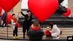 北京的一名家长和孩子一起游玩拍照。（2021年2月13日）