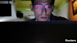 FILE - Vietnamese Internet activist Nguyen Lan Thang chats on Facebook at a cafe in Hanoi November 27, 2013.
