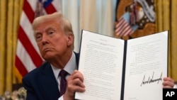 FILE - President Donald Trump holds up an executive order in Washington, Jan. 23, 2025. Since he took office, Trump signed several executive orders, including ones withdrawing the U.S. from the World Health Organization and the Paris Climate Agreement.