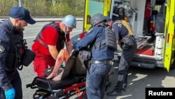Policajci i medicinski radnici lzbrinjavaju ranjenog lokalnog stanovnika nakon ruskog zračnog napada, u Harkovu, Ukrajina, 9. aprila 2024.
