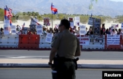 A police officer looks on as protesters line one side of a roadway leading to Sunnylands where U.S. President Obama prepares to host leaders from Southeast Asia at the ASEAN Summit in Rancho Mirage, California, Feb. 15, 2016.