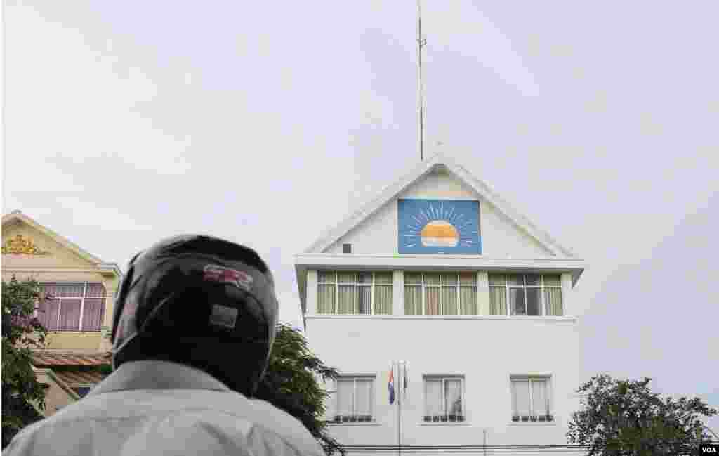 បុរស​ម្នាក់​អង្គុយ​ចាំ​ដំណឹង នៅមុខ​ទីស្នាក់ការ​កណ្ដាល​គណបក្ស​សង្គ្រោះ​ជាតិ ស្របពេល​ដែល​សមត្ថកិច្ច​បាន​ព្យាយាម​តាម​ស្កាត់​ឡាន​របស់​លោក កឹម សុខា អនុប្រធាន​គណបក្ស​នេះ កាលពីថ្ងៃព្រហស្បតិ៍ ទី២៦ ខែឧសភា ឆ្នាំ២០១៦។ (អូន ឆេងប៉រ/VOA)