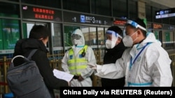 ប៉ូលិសនិងបុគ្គលិកដែលពាក់ឧបករណ៍ការពារ ត្រួតពិនិត្យឯកសាររបស់អ្នកដំណើរម្នាក់នៅច្រកចូលស្ថានីយ៍រថភ្លើងមួយ បន្ទាប់ពីមានការរឹតបន្តឹងការធ្វើដំណើរ ដើម្បីទប់ស្កាត់ការរីករាលដាលនៃវីរុសឆ្លង កូវីដ១៩នៅទីក្រុង Xian ខេត្ត Shaanxi ប្រទេសចិន ថ្ងៃទី២៣ ខែធ្នូ ឆ្នាំ២០២១។ (Reuters)