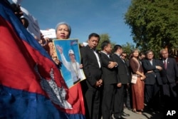 FILE - A supporter of the opposition Cambodia National Rescue Party holds a poster of the party leader Kem Sokha during a rally joined by lawmakers near an appeals court in Phnom Penh, Cambodia, Sept. 26, 2017.