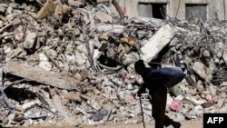 បុរសចាស់ជរាប៉ាឡេស្ទីនម្នាក់ដើរកាត់សំណង់អគារដែលរងការបំផ្លិចបំផ្លាញដោយសារការបាញ់គ្រាប់ផ្ទុះពីសំណាក់កងកម្លាំងយោធាអ៊ីស្រាអែល នៅតំបន់ហ្កាហ្សា កាលពីថ្ងៃទី ១៩ ខែឧសភា ២០២១។