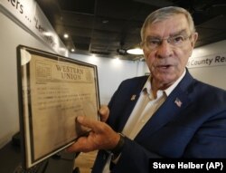 In this May 6, 2019, photo, owner Ken Parker, displays a copy of an original telegram sent announcing fatalities of the Bedford Boys during an interview at a tribute center for the Bedford Boys in Bedford, Virginia. Twenty Bedford men were killed on D-Day