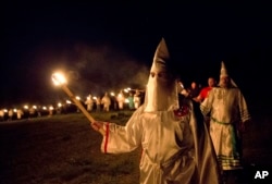 In this Saturday, April 23, 2016 photo, members of the Ku Klux Klan participate in cross burnings after a "white pride" rally in rural Paulding County near Cedar Town, Ga.