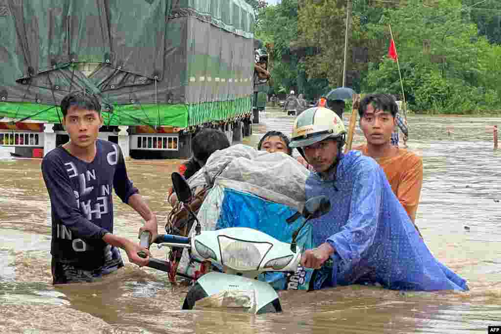People wade through flood waters in Thagaya in Myanmar's Bago region following heavy rains in the aftermath of Typhoon Yagi.