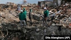 In this October 2, 2018 photo, volunteers of the humanitarian wing of the Islamic Defenders Front examine the damage caused by the earthquake and liquefaction at Balaroa neighborhood in Palu, Central Sulawesi, Indonesia.