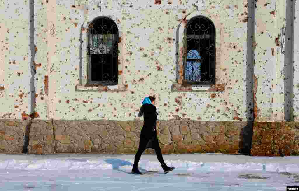 A woman walks outside St. Iveron Convent, which was heavily damaged by artillery and gun fire during battles for the local airport in the course of Russia-Ukraine conflict, in Donetsk, a Russian-controlled region of Ukraine.