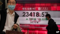 A man wearing a face mask walks past a bank's electronic board showing the Hong Kong share index at Hong Kong Stock Exchange Wednesday, March 25, 2020. Shares have advanced in Asia after the Dow Jones Industrial Average surged to its best day since 1933 a