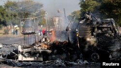 Un habitant passe devant un camion incendié près de la route où les manifestants sont passés à Atteridgeville, à l'ouest de Pretoria, Afrique du Sud, le 21 juin 2016.