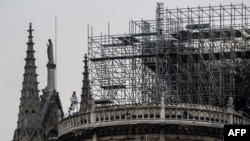 Trabajadores en el techo de la catedral de Notre-Dame de Paris, una semana después de un incendio que devastó la catedral.