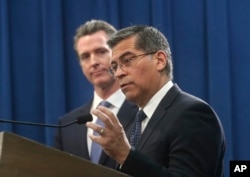 FILE - California Attorney General Xavier Becerra (R) accompanied by Gov. Gavin Newsom, announces California's intent to sue President Donald Trump over his emergency declaration to fund a wall on the U.S.-Mexico border, Feb. 15, 2019, in Sacramento,