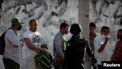 Un policía estatal habla con migrantes cerca del refugio "Casa INDI" donde varias personas han resultado infectadas con COVID-19 en Monterrey, México, el 12 de junio de 2020.