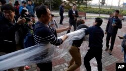 Protesters, center left, and center, take away the balloon from North Korean defector, right, during a rally in Paju, north of Seoul, South Korea, Saturday, Oct. 25, 2014.