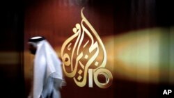 ARCHIVO: Un empleado de la cadena de televisión qatarí Al Jazeera camina frente al logo del canal en Doha, Qatar.