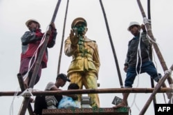 FILE - workers clean a vandalized statue of Myanmar independence hero Gen. Aung San, in Myitkyina, capital of Kachin state, Myanmar, July 23, 2018.