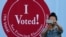 A woman takes a photo in front of an I Voted sign at a San Francisco Department of Elections voting center in San Francisco, Nov. 2, 2020.