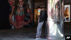 Beijing မြို့ရှိ အမျိုးသမီးအတွင်းခံ Victoria's Secret ကြော်ငြာအနီး Nike ဖိနပ်ဝတ်ထားတဲ့ အမျိုးသားတဦး Smart ဖုန်းသုံးနေစဉ် (မေ၊ ၂၁၊ ၂၀၁၉)