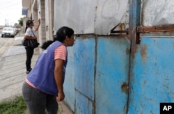 In this March 3, 2018 photo, public health workers go door-to-door in a neighborhood on the outskirts of Sao Paulo, Brazil, as part of a massive campaign to vaccinate people against yellow fever.