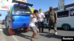 A man gets punished for not wearing a protective face mask during large-scale social restrictions to prevent the spread of the coronavirus disease (COVID-19) in Padang, West Sumatra Province, Indonesia May 15, 2020