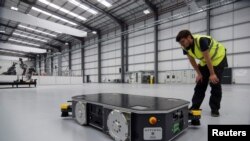 An engineer at UK electric van and bus maker Arrival inspects a specially developed autonomous robot at the startup's low-cost "microfactory" in Bicester, Britain, August 3, 2021. Picture taken August 3, 2021. REUTERS/Nick Carey