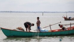 Fishermen navigate their boats near a development area where a part of Teuk Chhou bay is infilled, affecting fish stock in Kampot province, on October 3, 2021.
