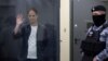 ARCHIVO - El reportero del Wall Street Journal, Evan Gershkovich, detenido por cargos de espionaje, saluda detrás de una pared de vidrio de un recinto para los acusados ​​mientras asiste a una audiencia judicial en Moscú, Rusia, el 23 de abril de 2024.