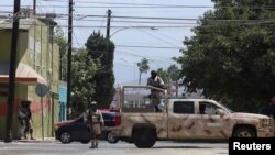 Fuerzas de seguridad patrullan una calle de Tijuana, México, donde algunos vehículos fueron incendiados por presuntos delincuentes el viernes 12 de agosto de 2022. Foto Reuters.
