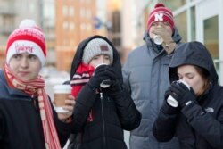 Mahasiswa Universitas Nebraska menyeruput cokelat panas ketika mereka pertandingan bola basket perguruan tinggi NCAA melawan Wisconsin, di Lincoln, Nebraska, 29 Januari 2019, di saat musim dingin.(Foto: AP)