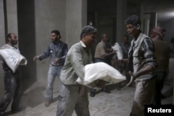 Men store bags of flour unloaded from a Red Crescent aid convoy in the rebel held besieged town of Jesreen, in the eastern Damascus suburb of Ghouta, Syria, March 7, 2016.
