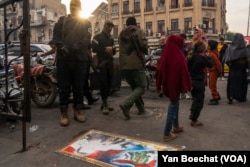 A picture of fallen dictator Bashar al-Assad is displayed on a sidewalk in Damascus, Syria, with residents stepping over it to show their anger against the regime, while HTS soldiers look on, Dec. 12, 2024.