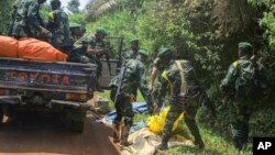 Des soldats des Forces de défense congolaises enlèvent les corps des victimes d'une attaque près de la ville d'Oicha, à 30 km de Beni, en République démocratique du Congo, le 23 juillet 2021. 