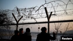 People look toward the north through a barbed-wire fence near the militarized zone separating the two Koreas, in Paju, South Korea, Dec. 21, 2017.