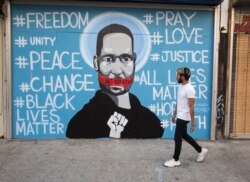 FILE - A man walks past a mural depicting George Floyd during a protest over the death of Floyd, in Los Angeles, May 31, 2020.