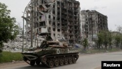 Pripadnici ruske vojske ispred uništenih stambenih zgrada u Popsanu, Ukrajina.