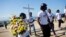 FILE - Youths of Cite Soleil carry flowers and a cross to a monument honoring the victims of the 2010 earthquake before a memorial service at Titanyen, a mass burial site north of Port-au-Prince, Haiti, Jan. 12, 2019.
