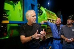 James Cameron talks with his crew in front of the DEEPSEA CHALLENGER following testing of the submersible in Jervis Bay, south of Sydney, Australia.