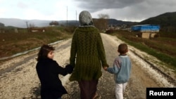 Siriyalik ayol farzandlari bilan Turkiya chegarasi yaqinidagi qochqinlar lagerida boshpana topgan. 