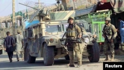 Afghan security forces keep watch in front of their armoured vehicle in Kunduz city, Afghanistan, Oct. 4, 2016. 
