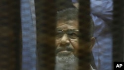 ប្រធានាធិបតី​ដែល​ត្រូវ​បណ្តេញ​ចេញ​ពី​តំណែង​ Mohammed Morsi លោក​ អង្គុយ​នៅ​ក្នុង​បន្ទប់​ឃុំ​កញ្ចក់​ ក្នុង​តុលាការ​អេហ៊្សីប​ ក្នុង​ទីក្រុង​ Cairo កាល​ពី​ថ្ងៃ​ទី​២១​ ខែ​មេសា​ ឆ្នាំ​២០១៥។