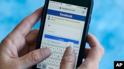 FILE - A Facebook start page is shown on a smartphone in Surfside, Florida. Aug. 21, 2018. The social media giant Facebook said late Wednesday Aug. 22, 2018, it has banned a quiz app for refusing to be audited and concerns that data on as many as 4 million users was misused, after it found user information was shared with researchers and companies.