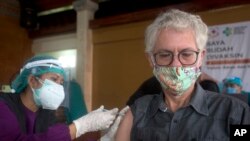 Seorang WNA divaksinasi COVID-19 dengan vaksin produksi AstraZeneca, saat pemerintah daerah Denpasar, Bali, menggelar vaksinasi massal, 22 Maret 2021. (AP Photo / Firdia Lisnawati).