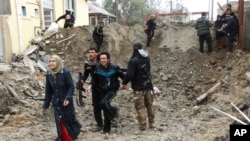 FILE - Iraqi security forces and allied Sunni tribal fighters help trapped civilians cross from neighborhoods under control of the Islamic State group to neighborhoods under control of Iraqi security forces in Ramadi, 70 miles (115 kilometers) west of Baghdad, Iraq, Jan. 4, 2016.