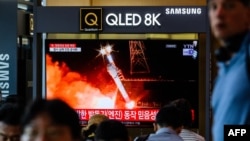 Sejumlah warga tampak duduk di dekat layar televisi di sebuah stasiun kereta di Seoul yang menampilkan berita gagalnya peluncuran satelit Korea Utara pada 28 Mei 2024. (Foto: AFP/Anthony Wallace)