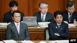 Japanese Prime Minister Shinzo Abe (R) and Finance Minister Taro Aso (L) show their sour faces at the Upper House's plenary session at the National Diet in Tokyo, February 6, 2013.